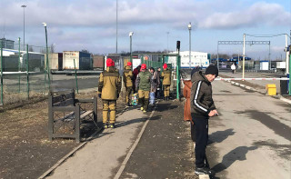 Волонтеры в форме Объединенного народного фронта встречают эвакуированных на границе с Донецкой народной республикой.